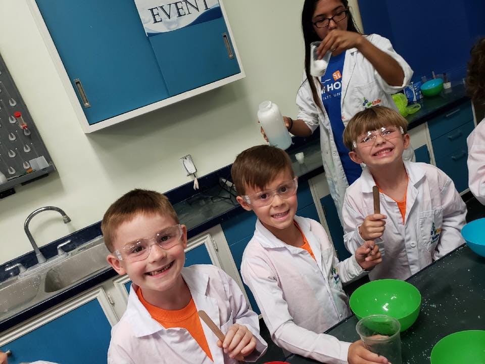 Children in lab coats and safety glasses in a science classroom