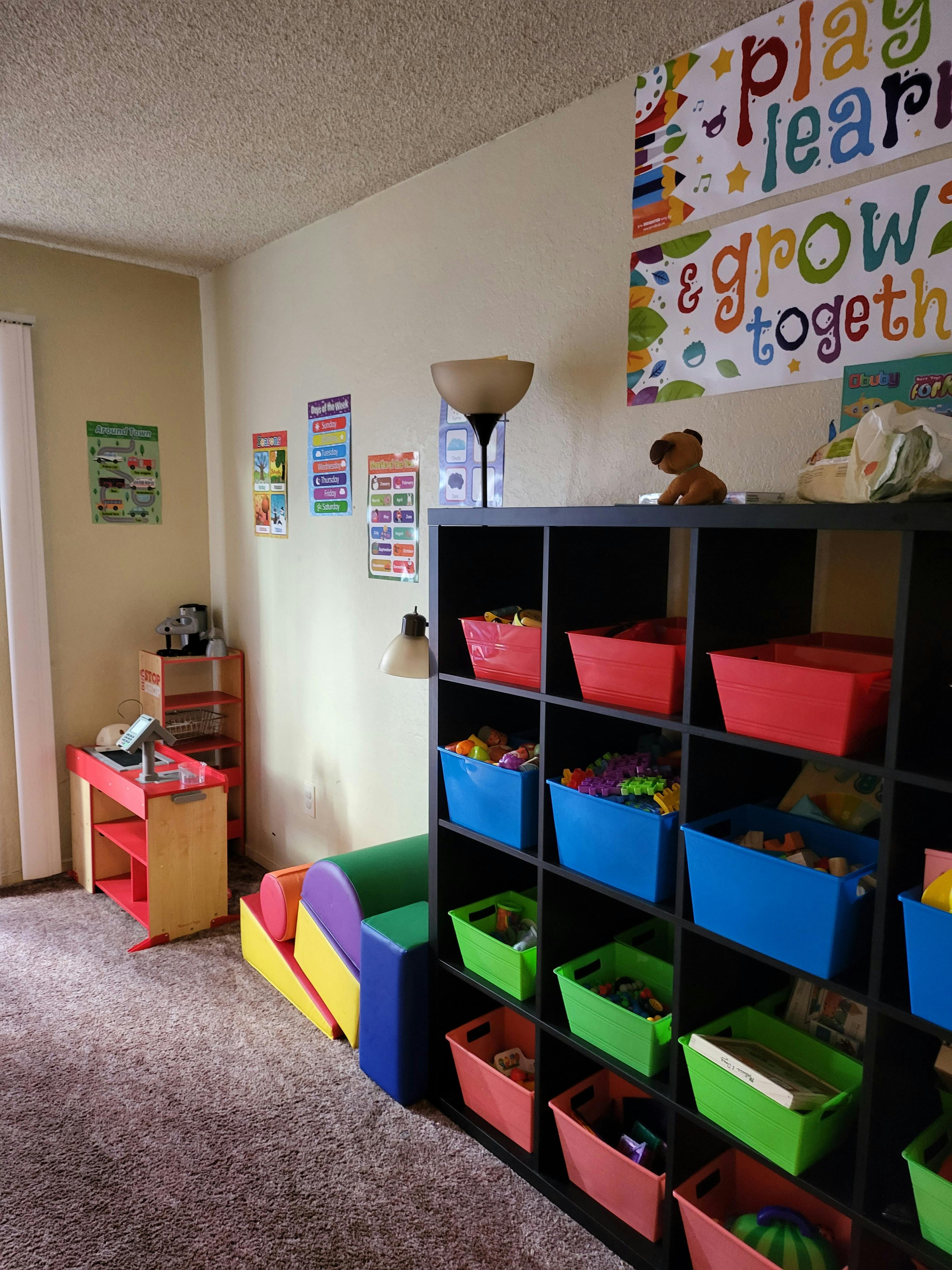 Playroom with cubby shelves filled with colorful bins, small table, and wall decor