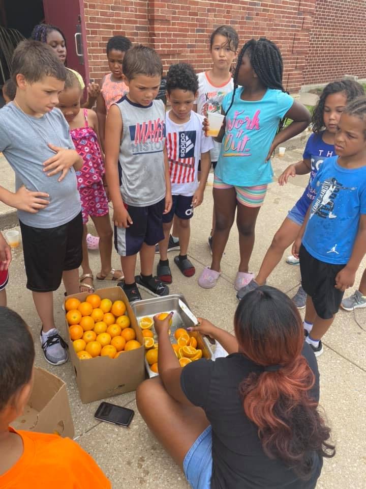 Person cutting oranges for a group of children