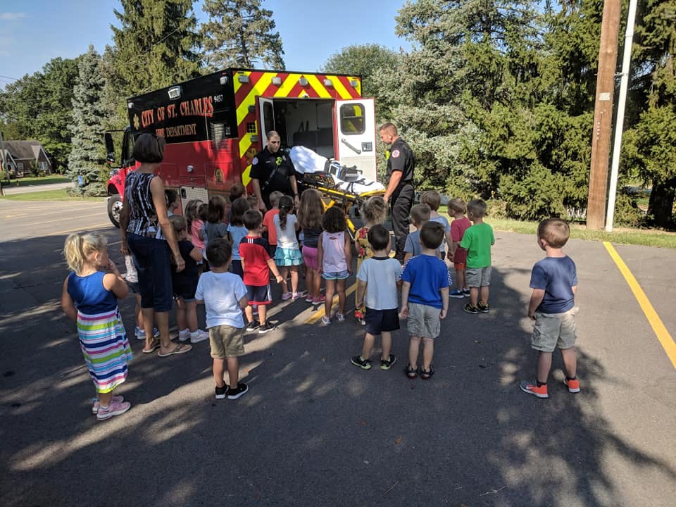 Children gathered around an ambulance with two adults