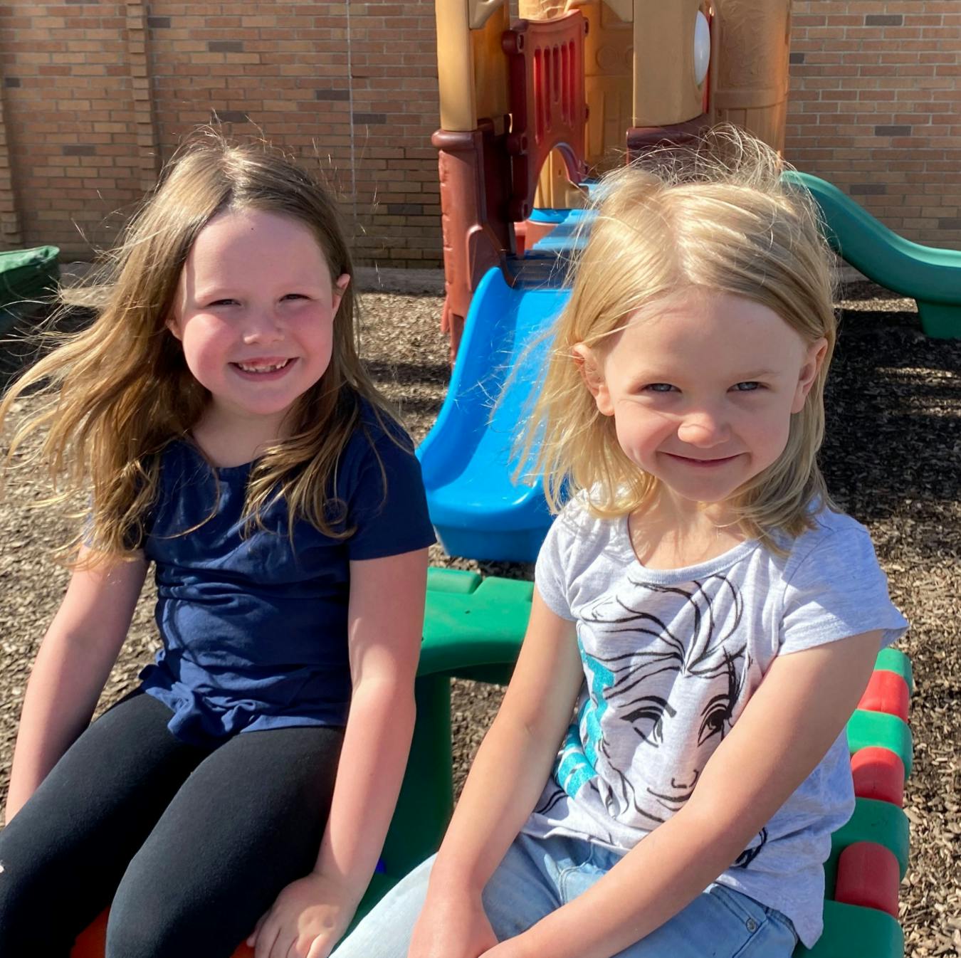 Two children sitting on playground equipment