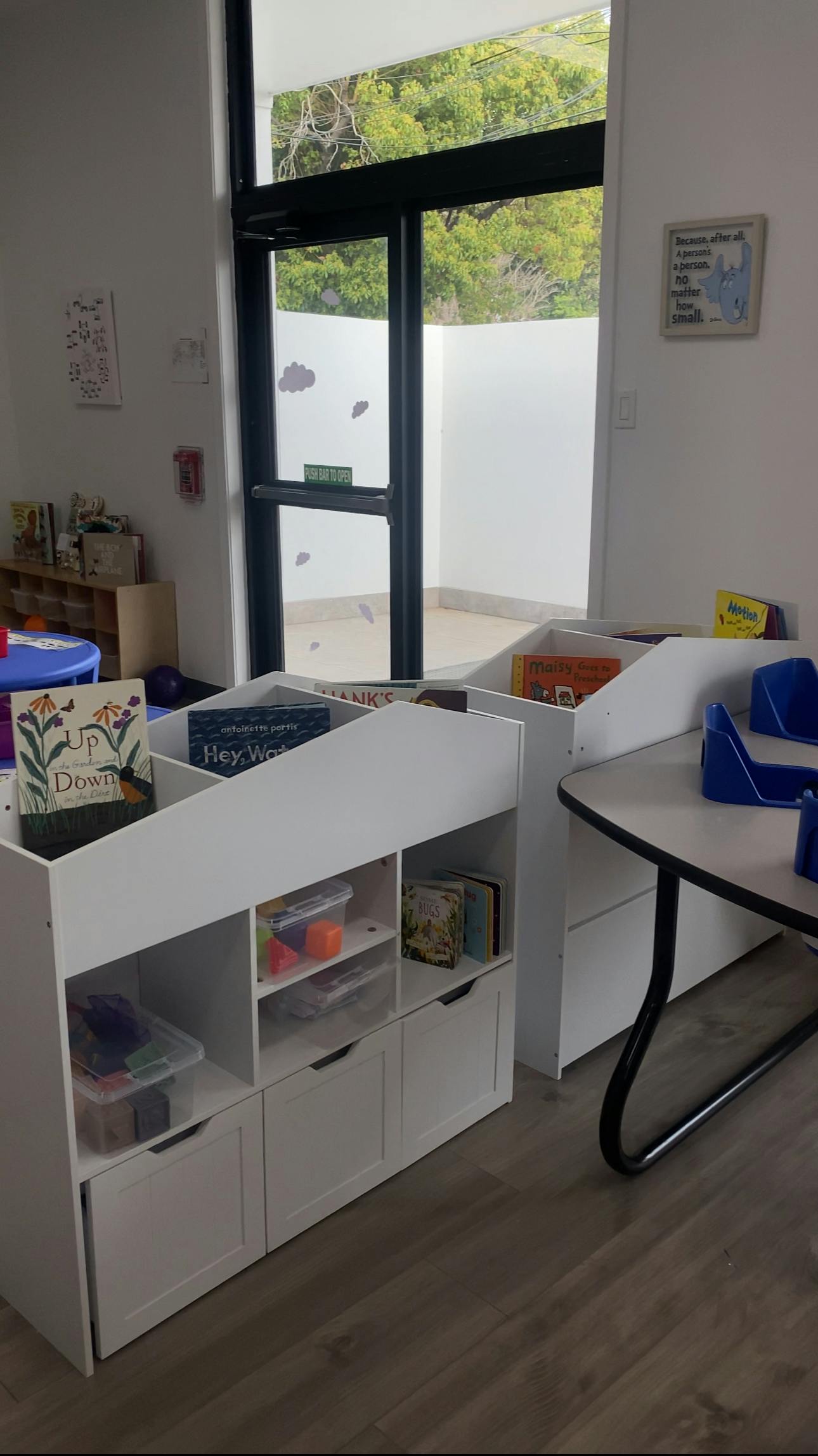 Bookshelves and a table in a room with a large window