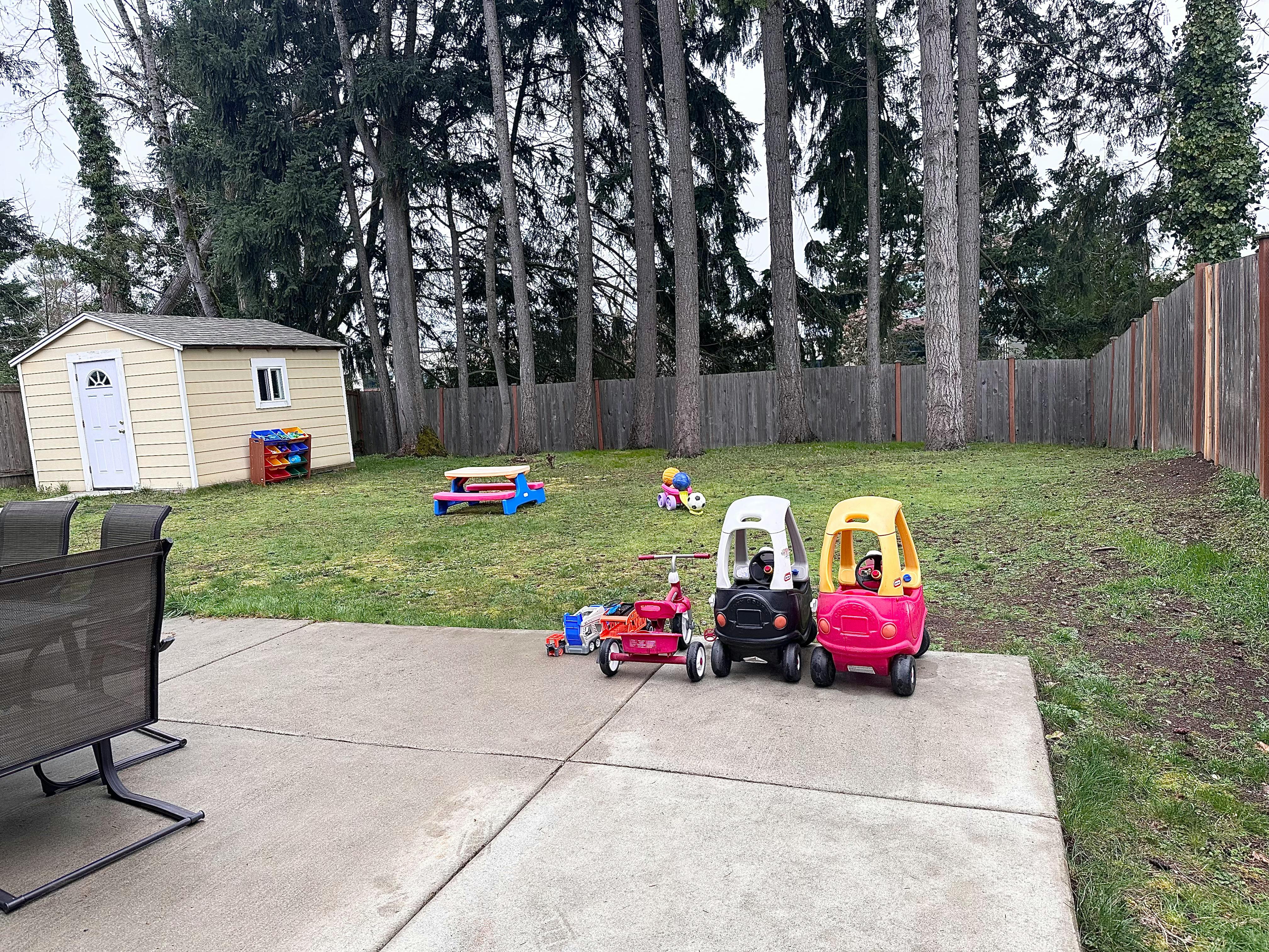 Backyard with shed, play cars, and picnic table