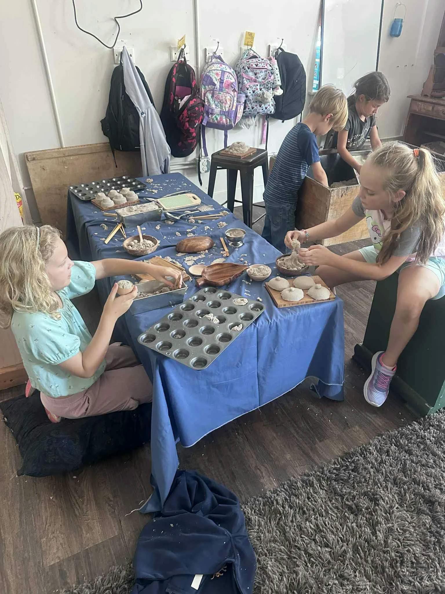 Several children making crafts at a table with a muffin tin and bowls