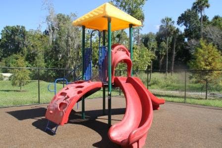 Red and yellow playground structure with slides and climbing wall