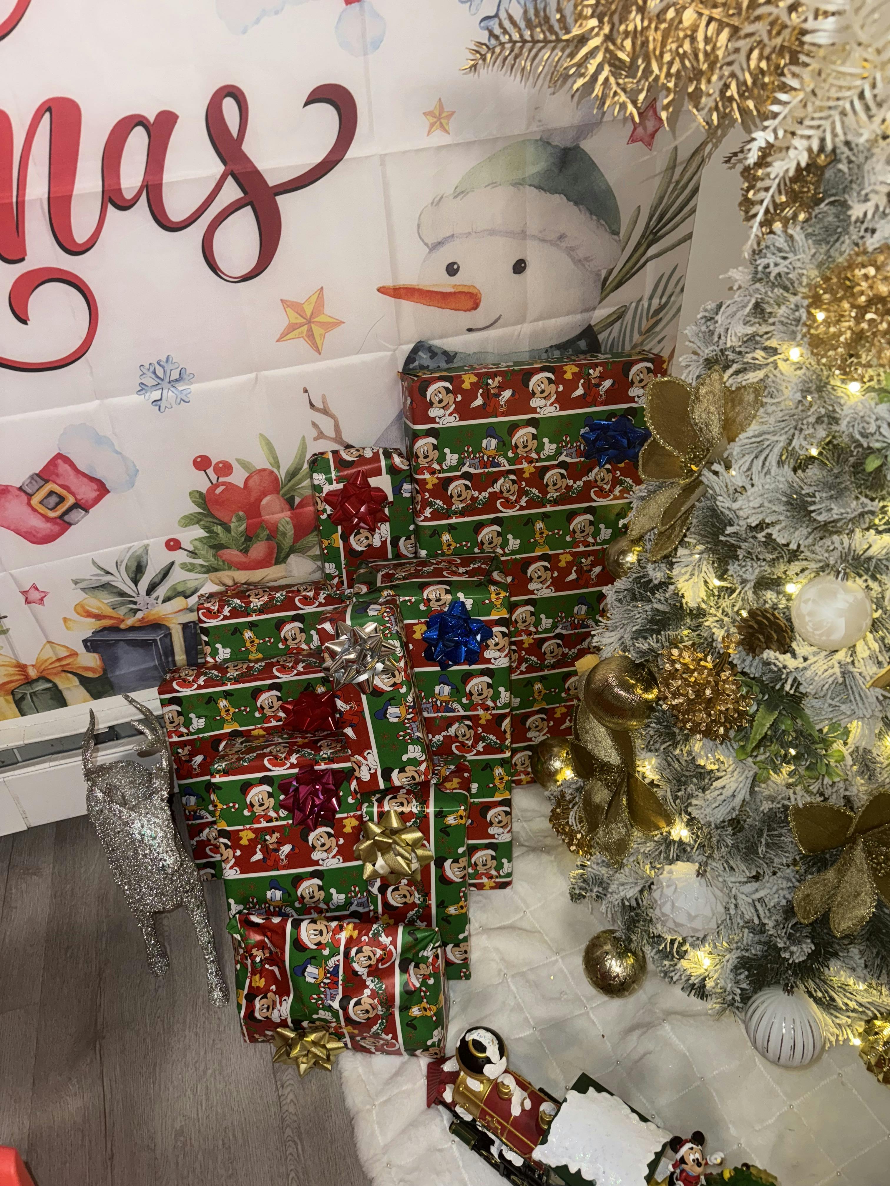 Christmas presents wrapped in festive paper next to a decorated Christmas tree
