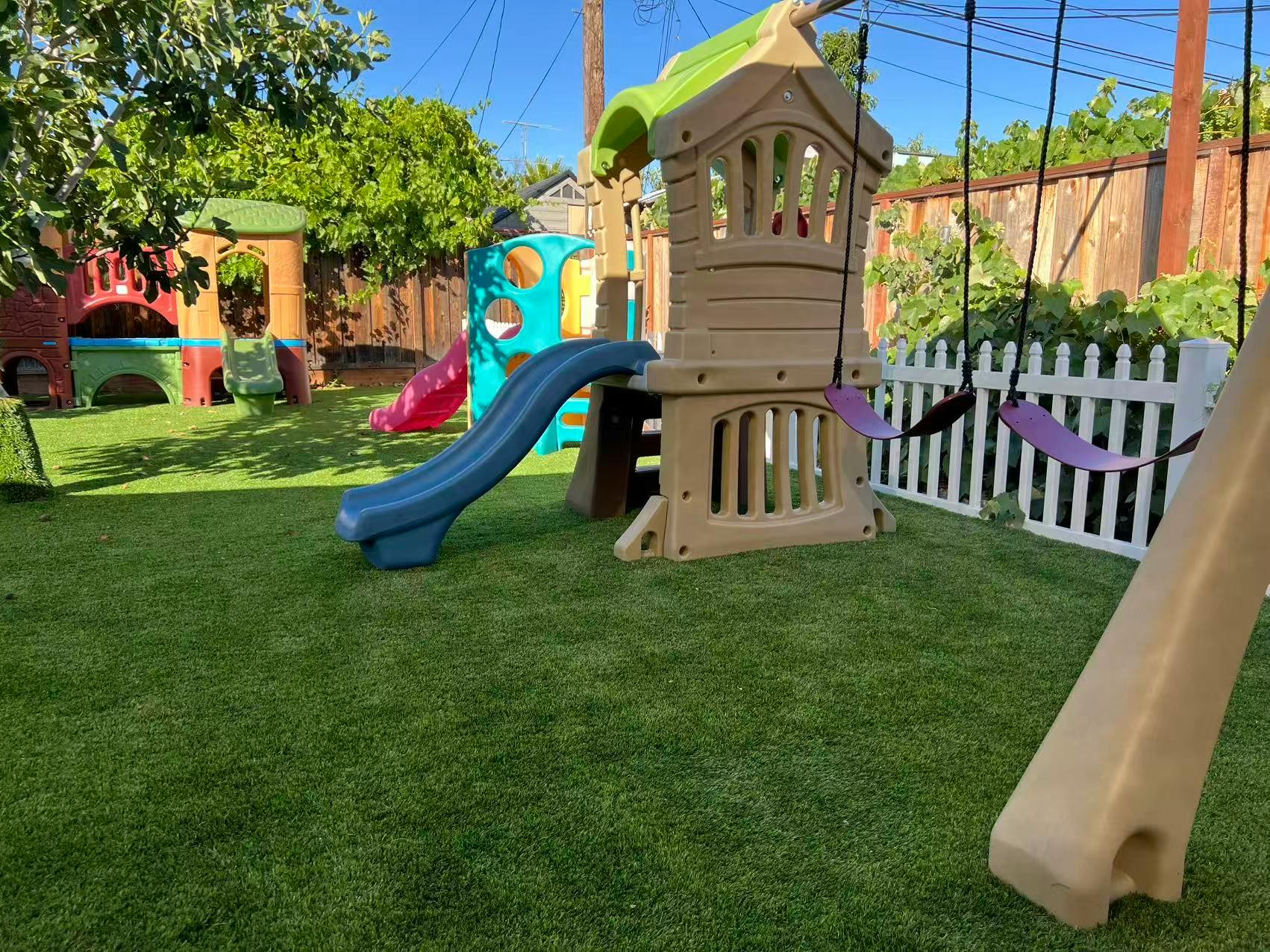 Plastic outdoor playground with slides and swings on artificial turf