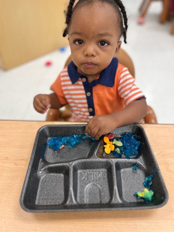 Child sitting at a table with a tray of food