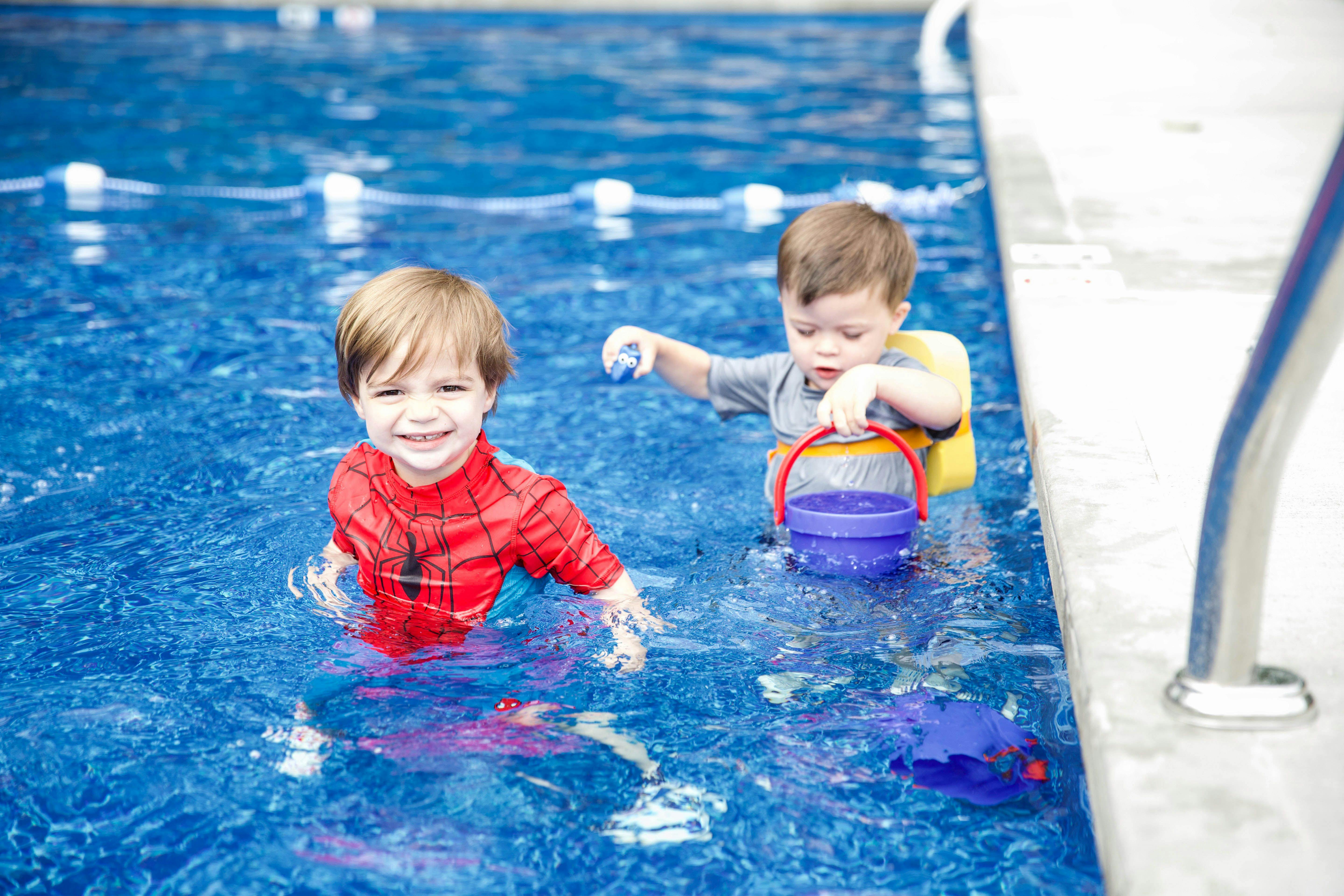 Two children playing with a bucket and toy in a swimming pool