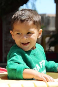 Child in a green shirt smiling