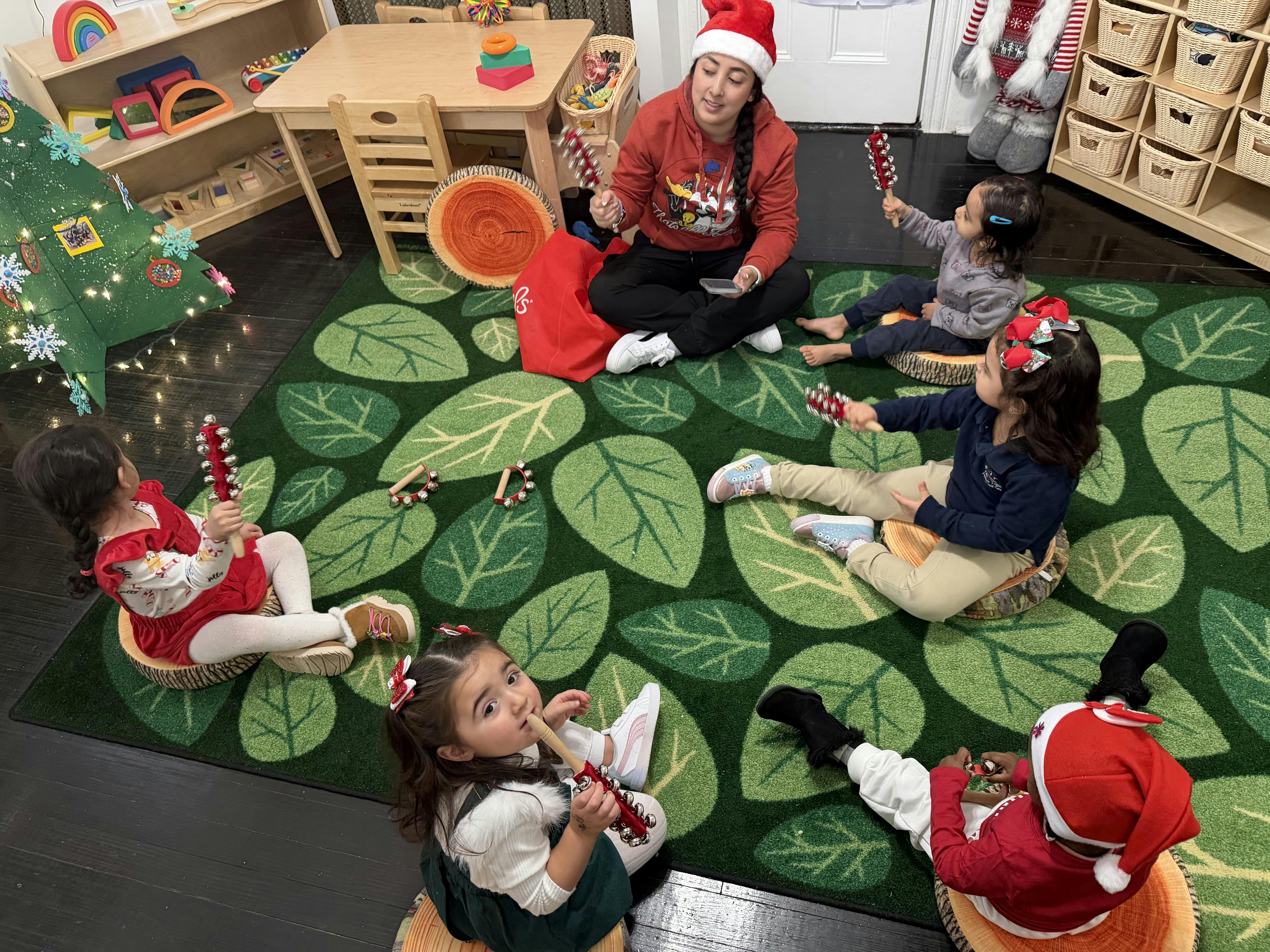 Adult and children sitting on a leaf-patterned rug, holding candy cane shakers