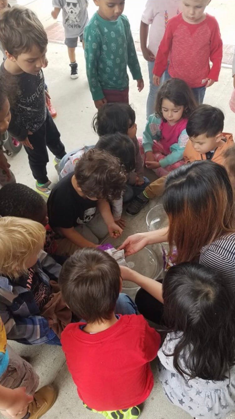 Adult and children gathered around a bowl on the floor
