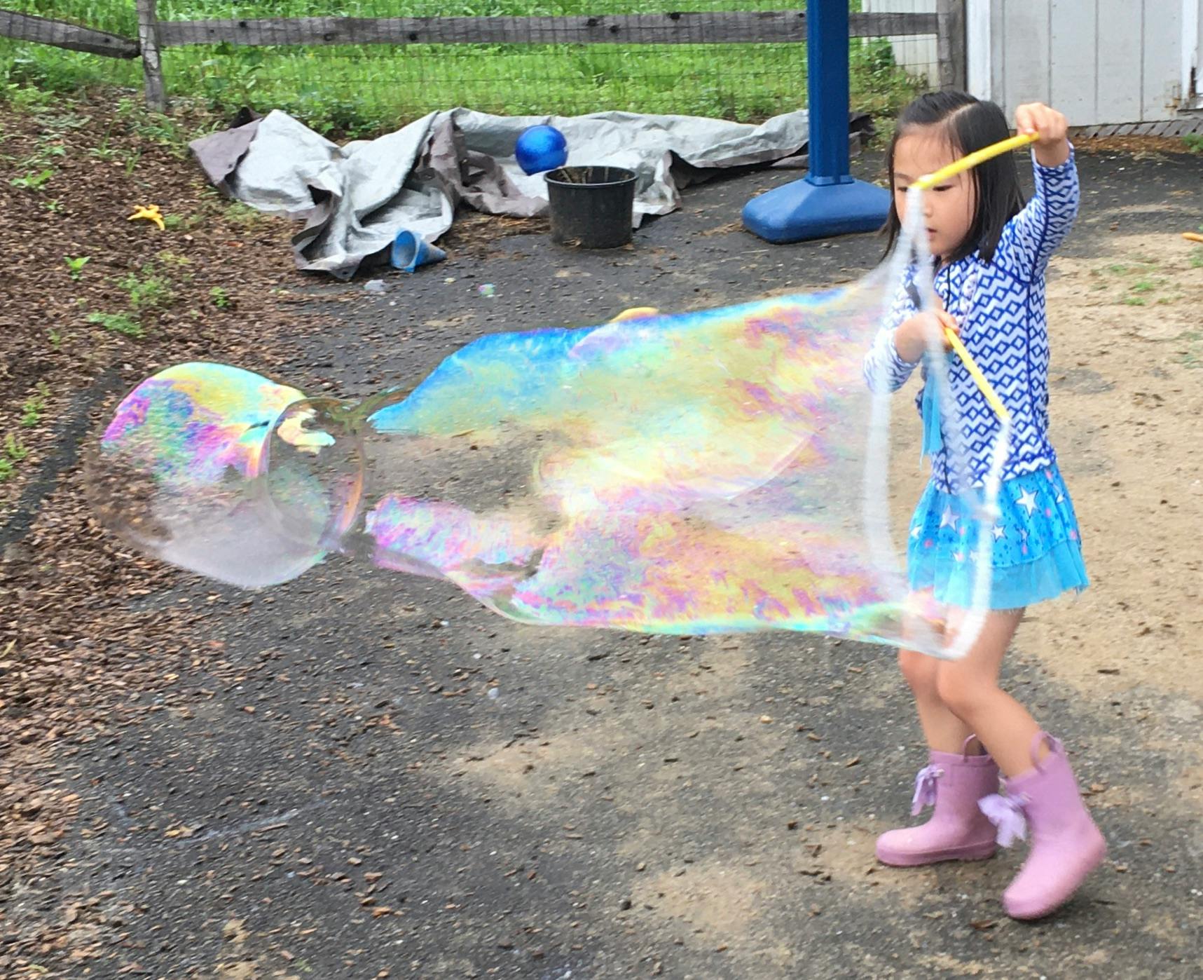 Child making large bubbles with a bubble wand