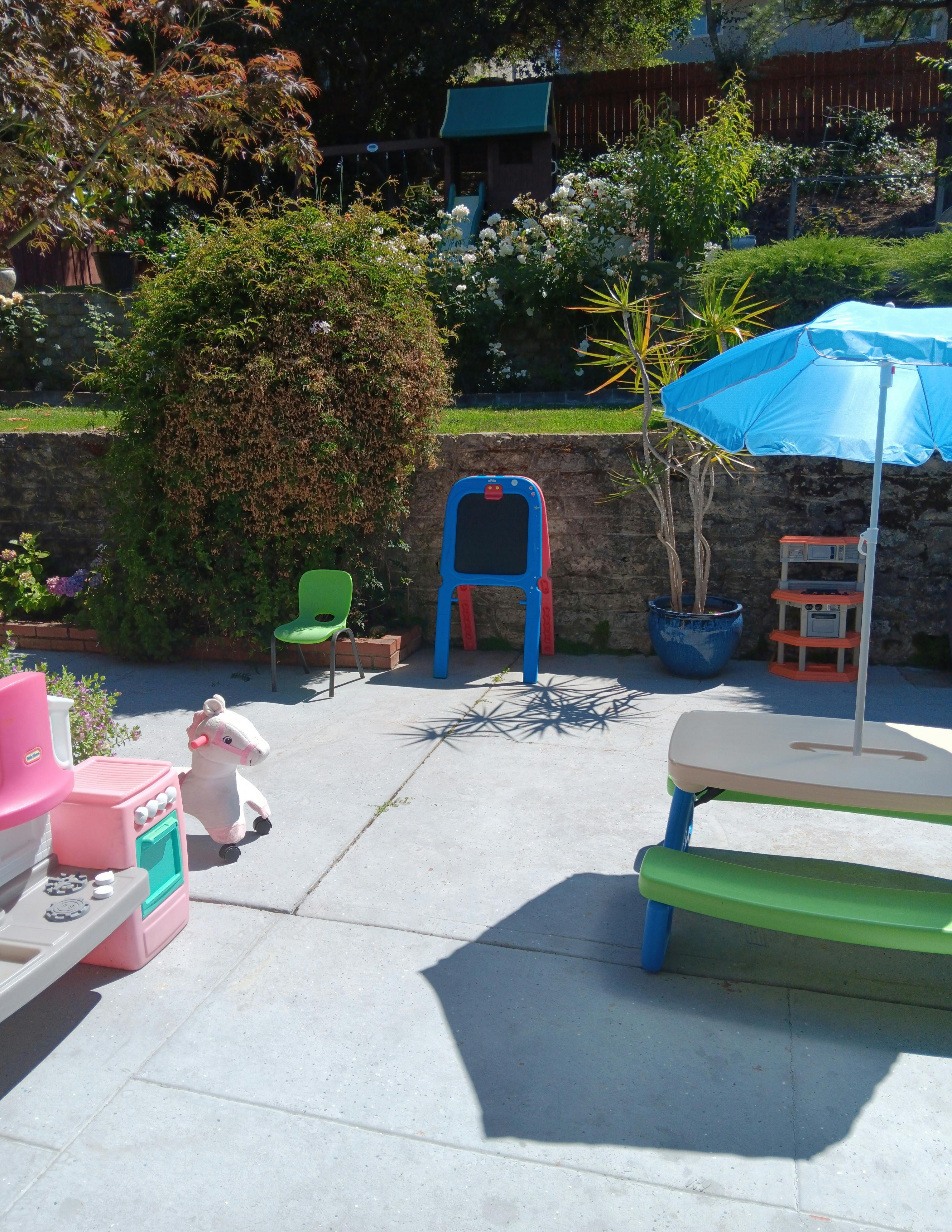 Patio with children's play kitchen, easel, and umbrella