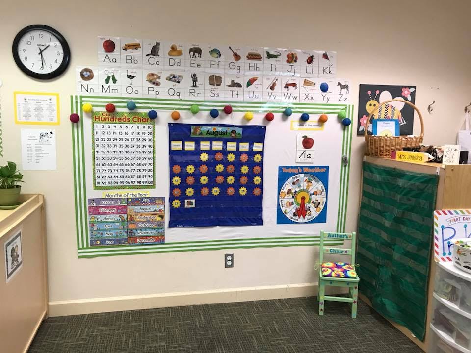 Classroom wall with a calendar, alphabet chart, and small chair
