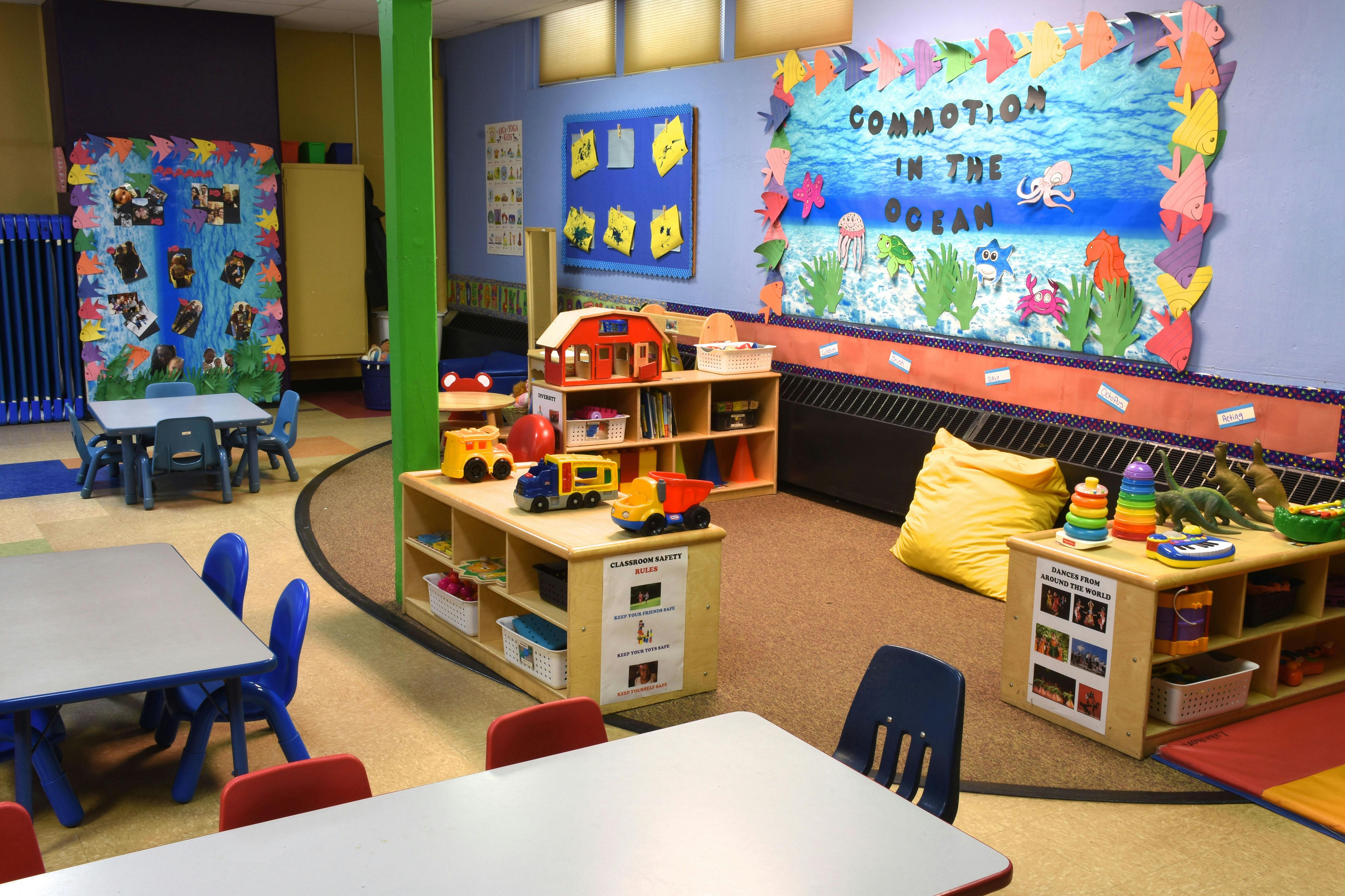 Classroom with tables, chairs, and shelves of toys