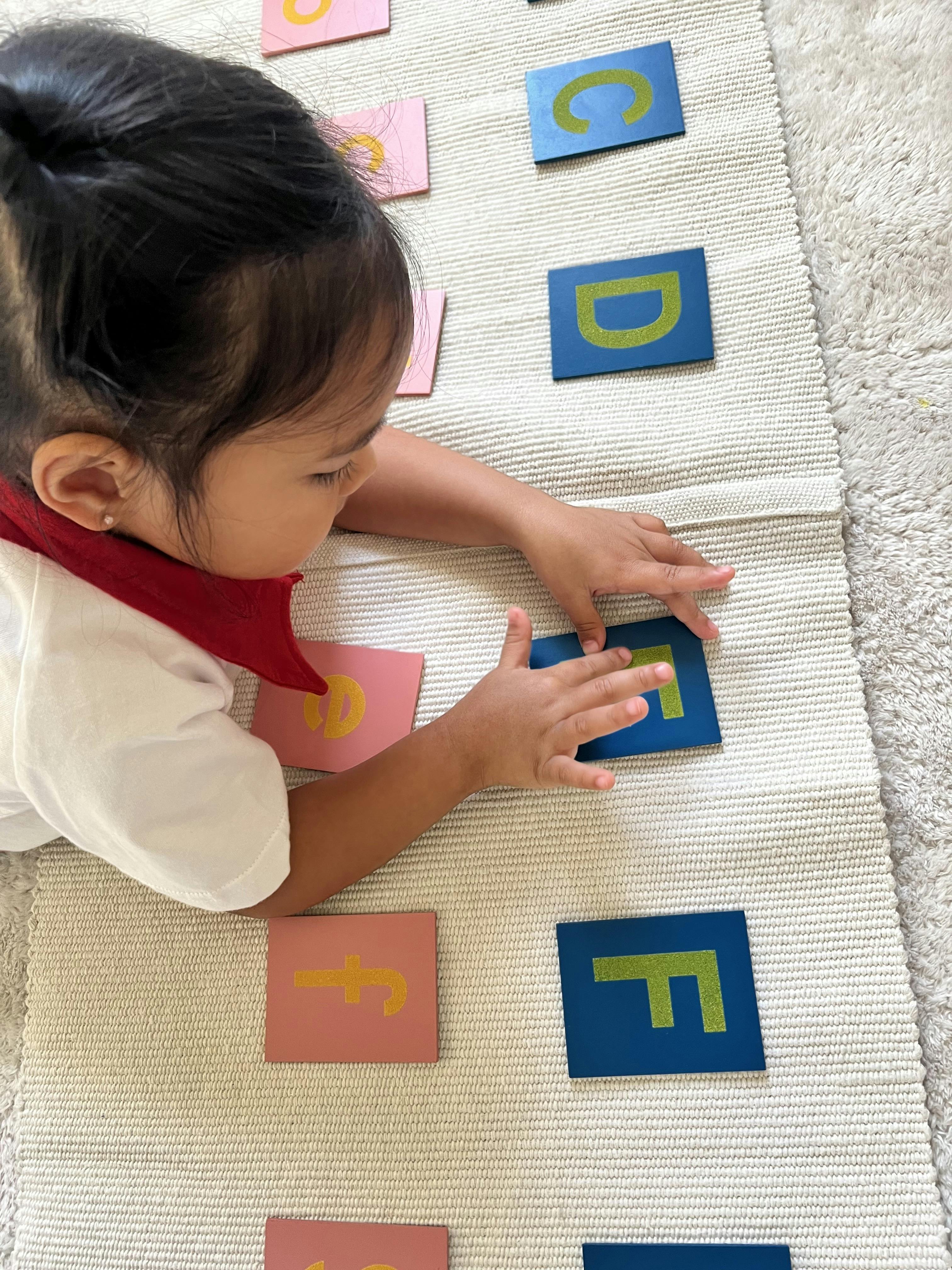 Child playing with alphabet letter tiles on a mat