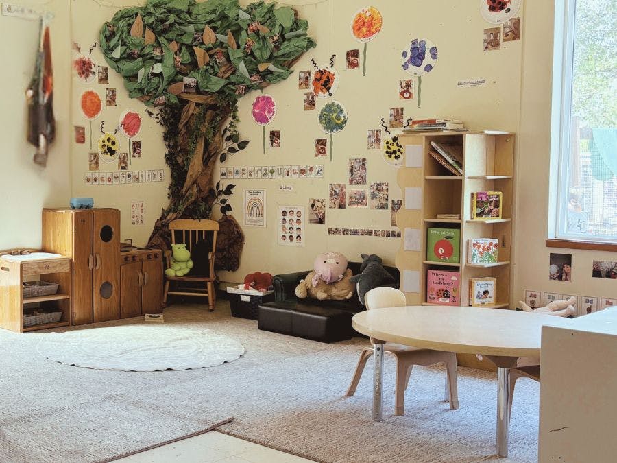 Playroom with a tree mural, small table and chairs, and shelves