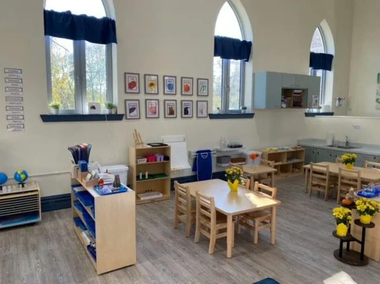 Classroom with small tables and chairs, shelves, and arched windows