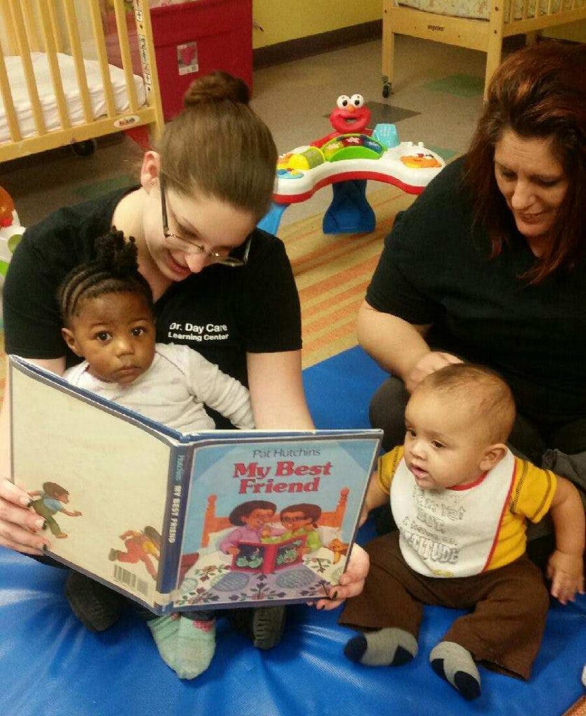 Two people reading a book to two babies