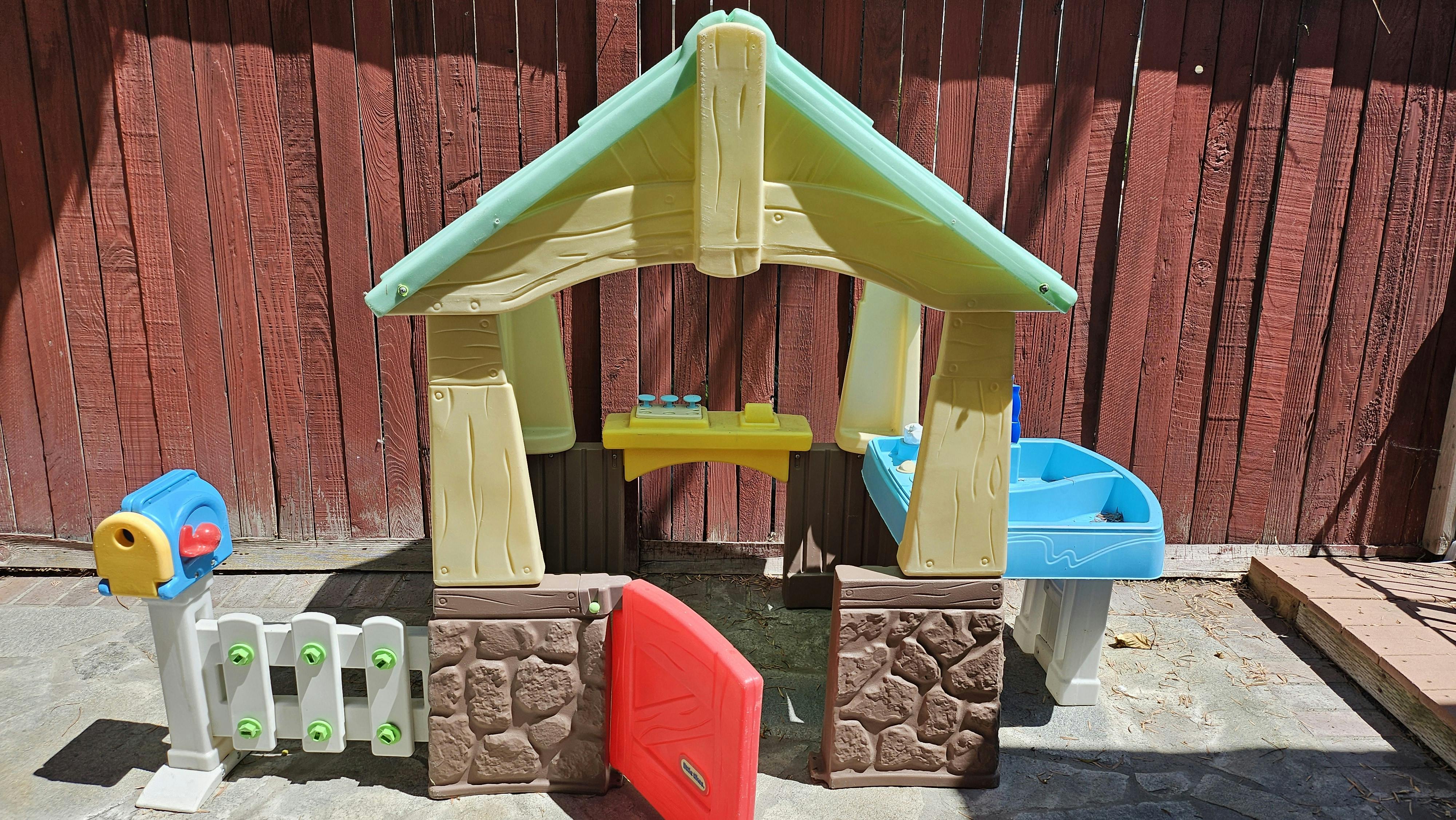 Child's plastic playhouse with a mailbox and fence