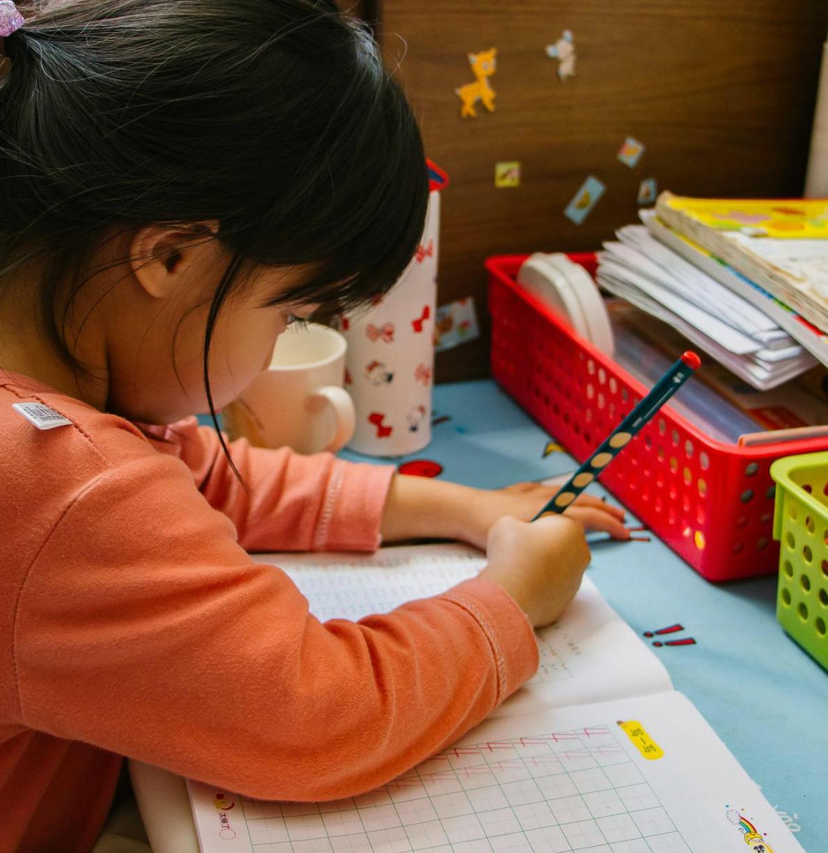 Child writing in a notebook with a pencil