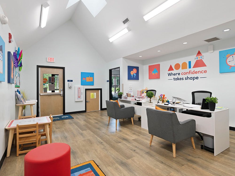 Reception area with a desk, chairs, and colorful artwork on the wall