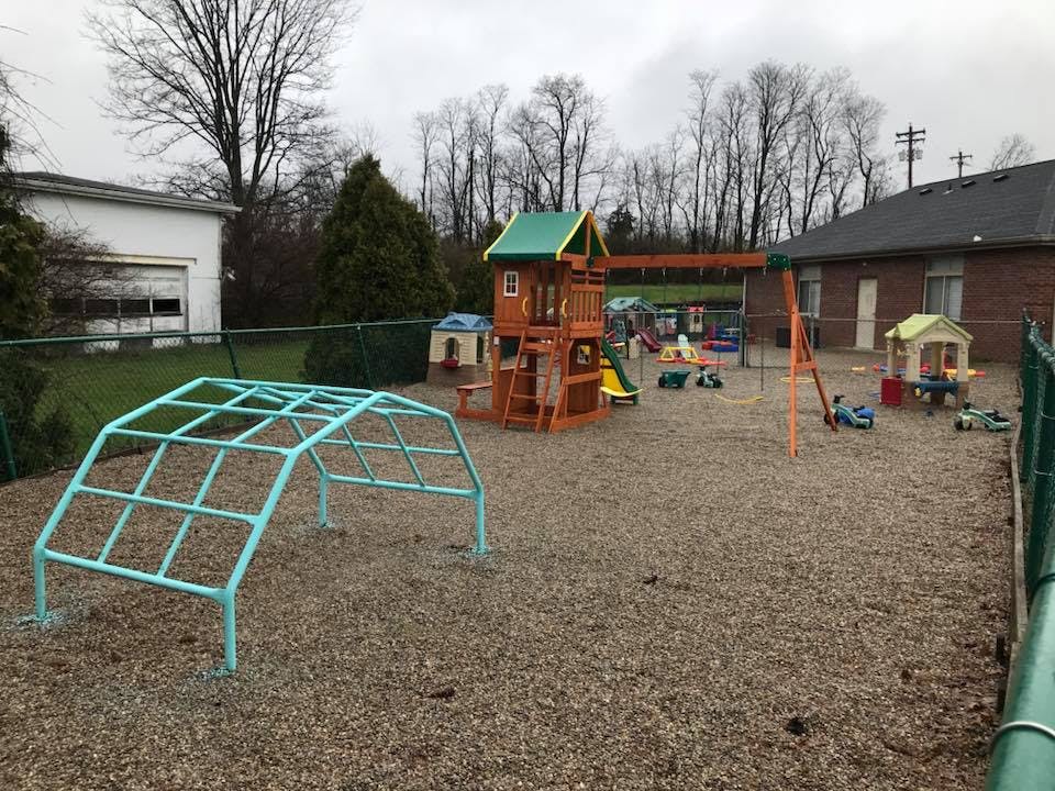 Outdoor playground with a climbing dome, swing set, and playhouse