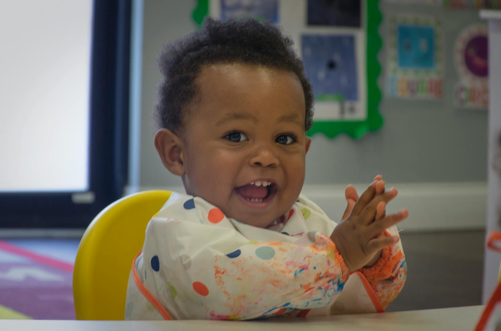 Child in a high chair clapping hands