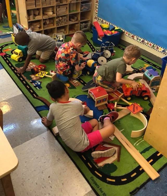 Children playing with toys on a road-themed rug