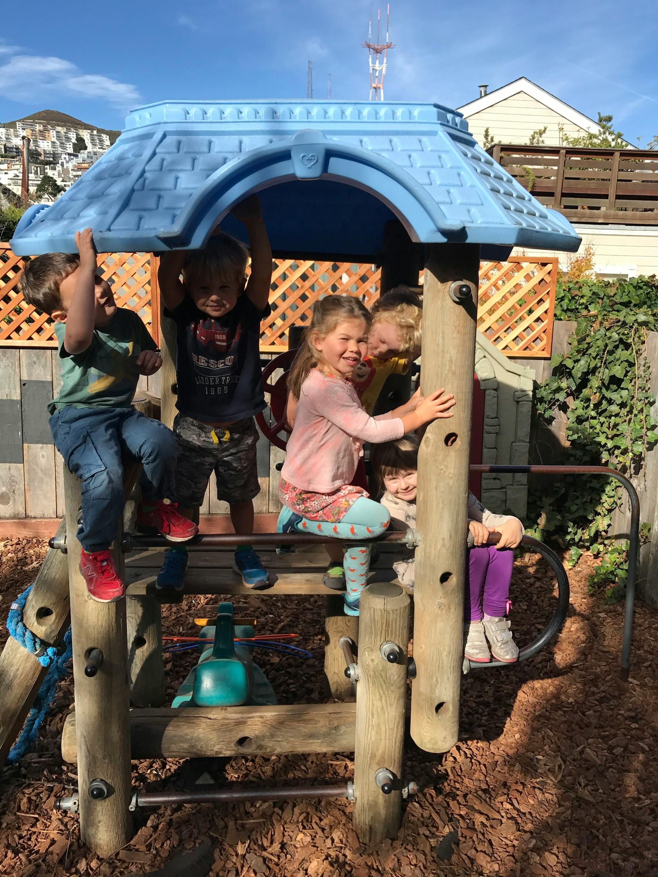 Children playing on a wooden and blue plastic play structure
