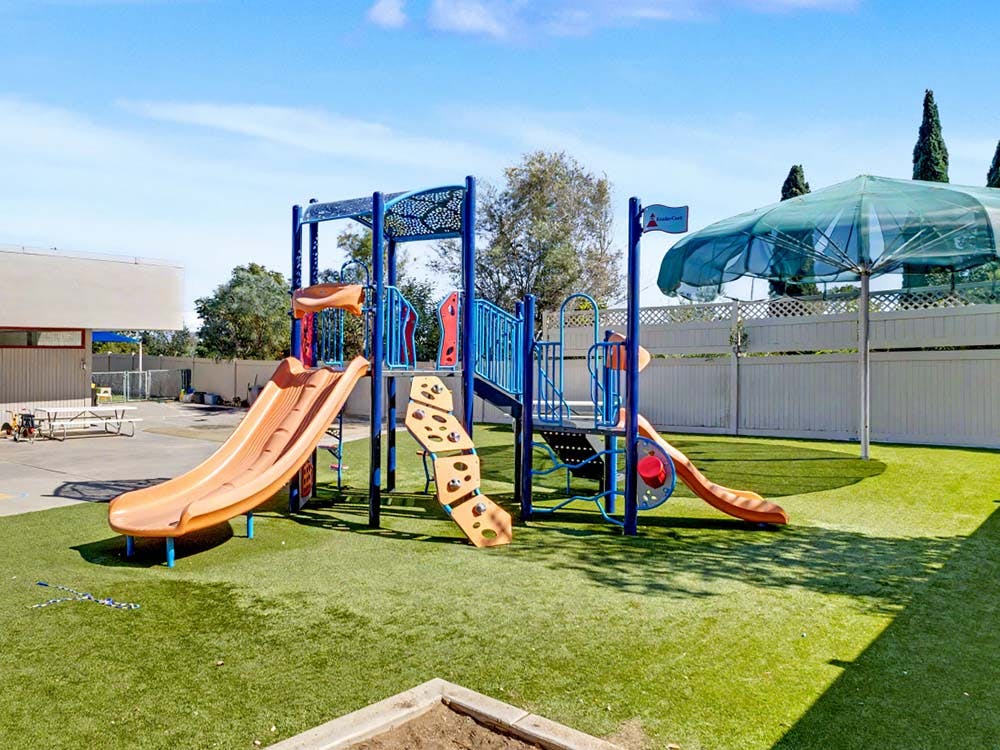 Playground with blue and orange slides on artificial turf