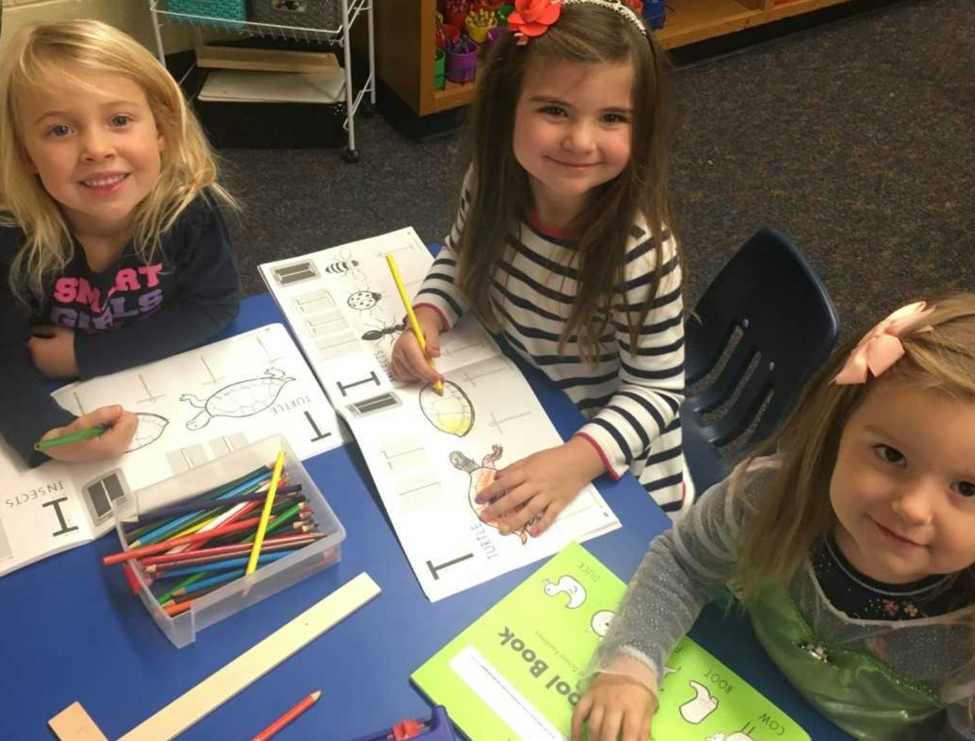 Three children drawing and coloring at a table