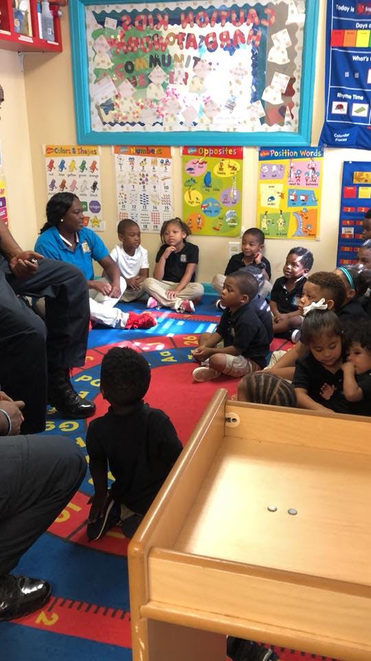 Adult and children sitting on a rug in a classroom