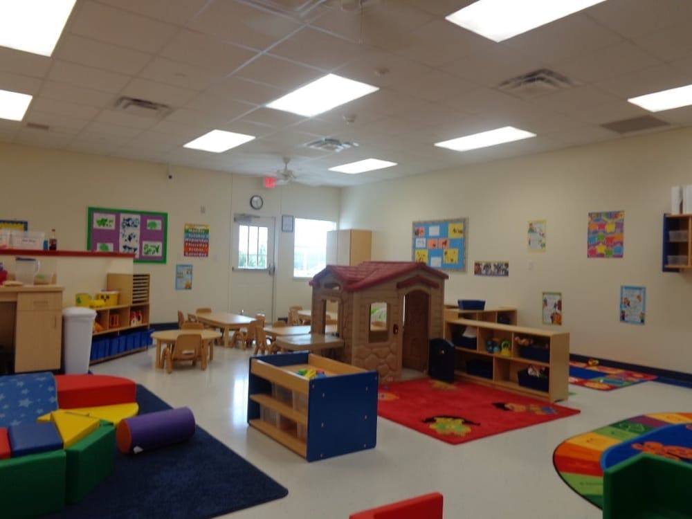 Empty classroom with small tables, chairs, and play structures