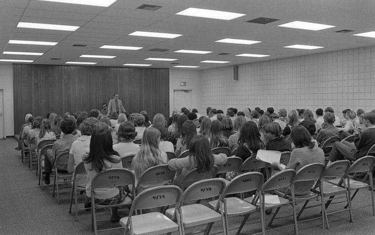People seated in rows facing a speaker at the front of a room