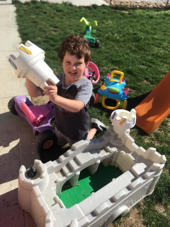 Child playing with a toy rocket and other toys outdoors