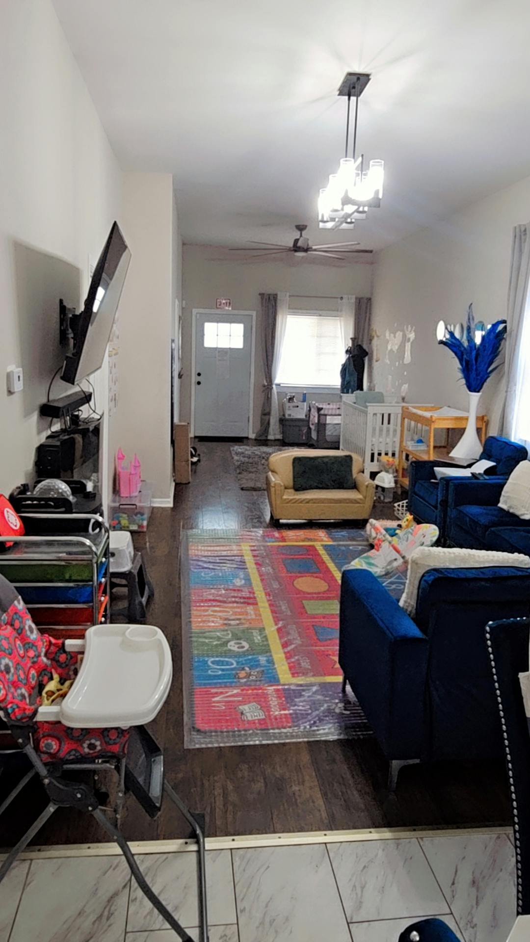 Living room with a high chair, television, sofas, and a colorful rug