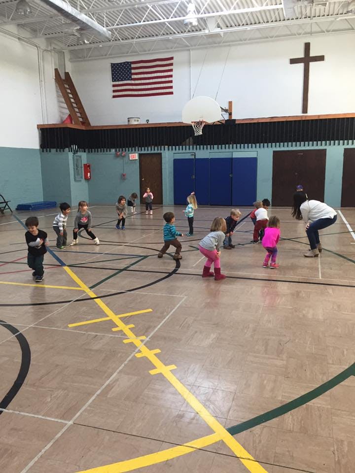 Children and an adult playing in a gymnasium