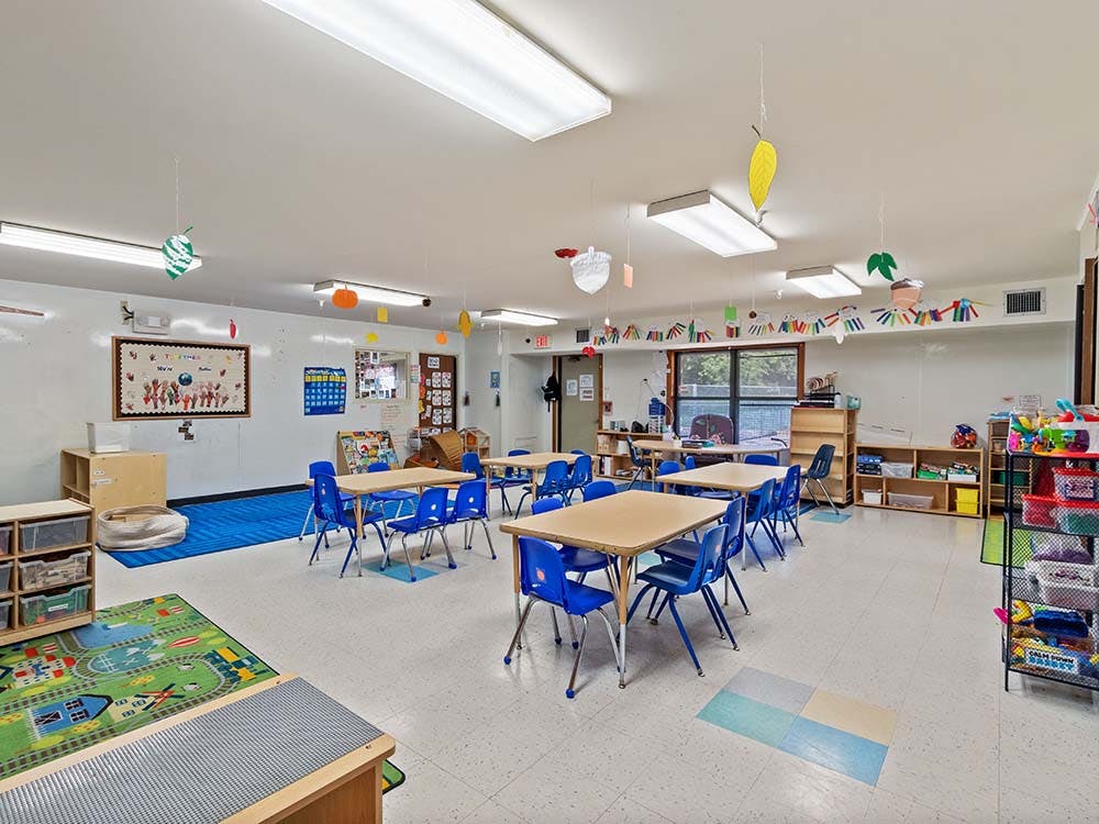 Classroom with small tables and chairs, colorful decorations, and learning materials