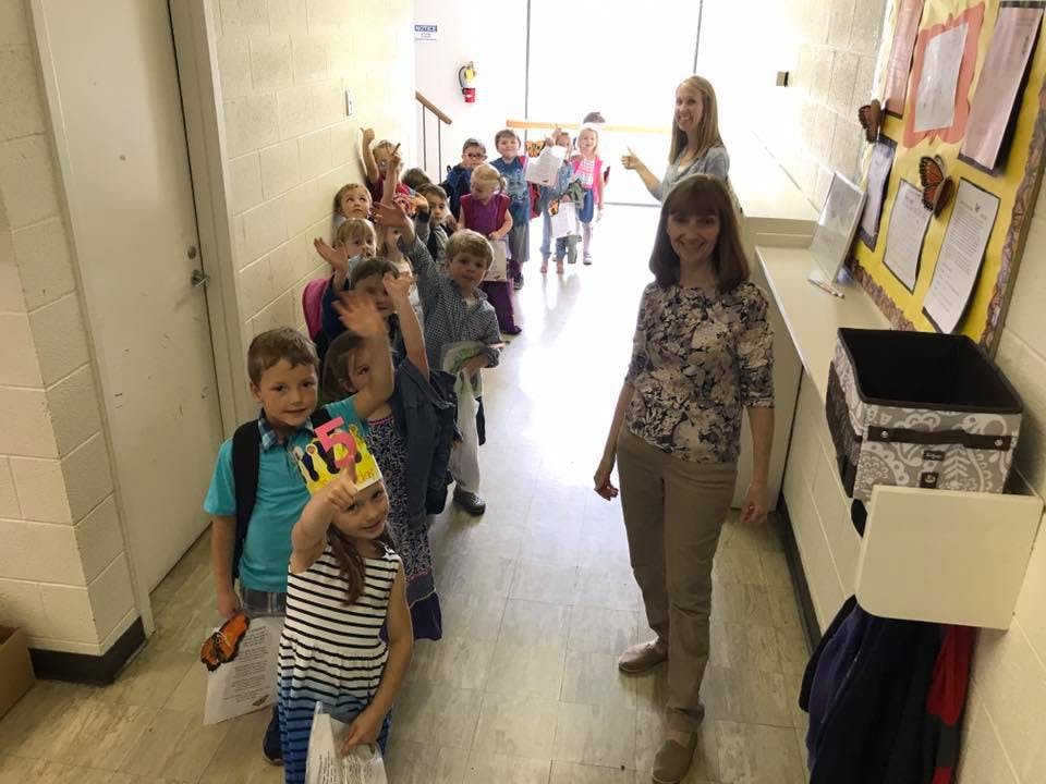 Adult and children in a line in a hallway