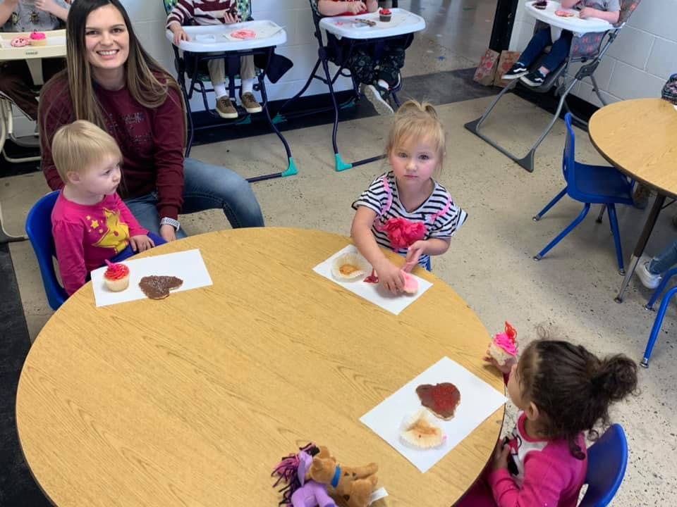 Adult and three children at a table with crafts