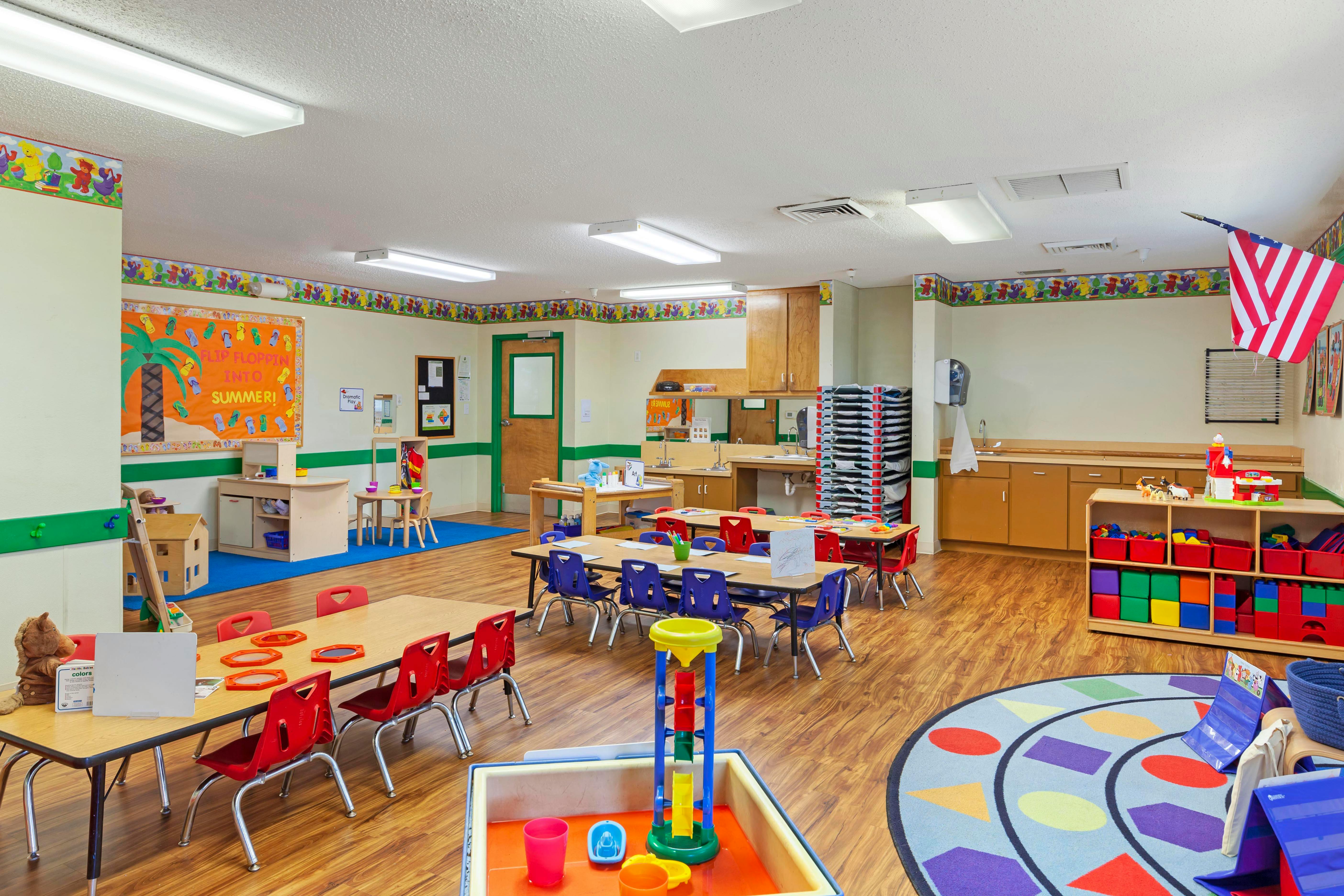 Empty colorful classroom with tables, chairs, and play areas