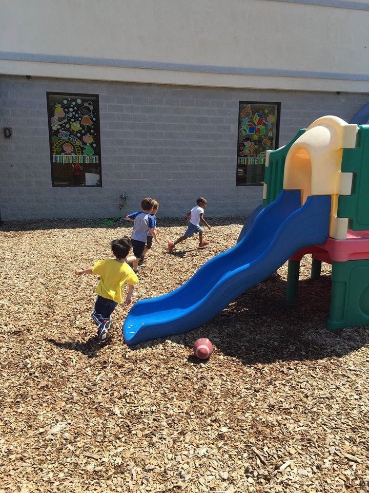 Children running on a playground near a slide