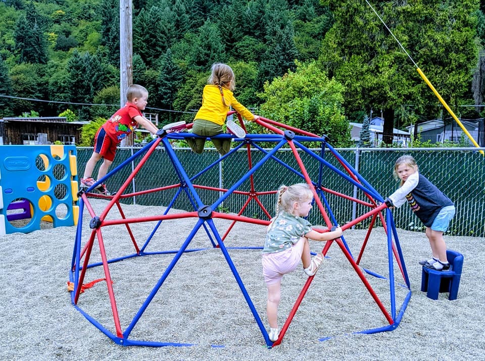 Children playing on a red and blue climbing dome on a playground