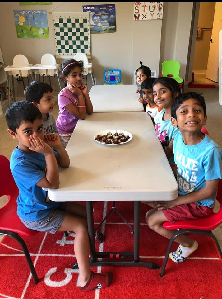 Children sitting at tables with a plate of food