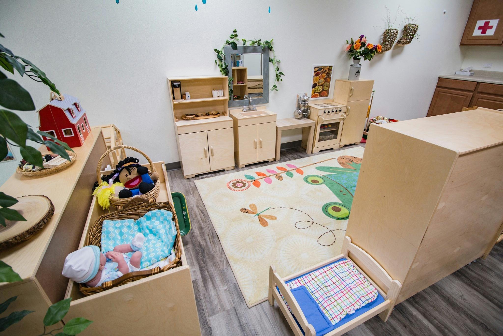 Playroom with a doll in a basket, toy kitchen, and patterned rug