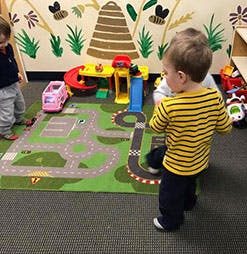Two children playing with toy cars on a road map rug