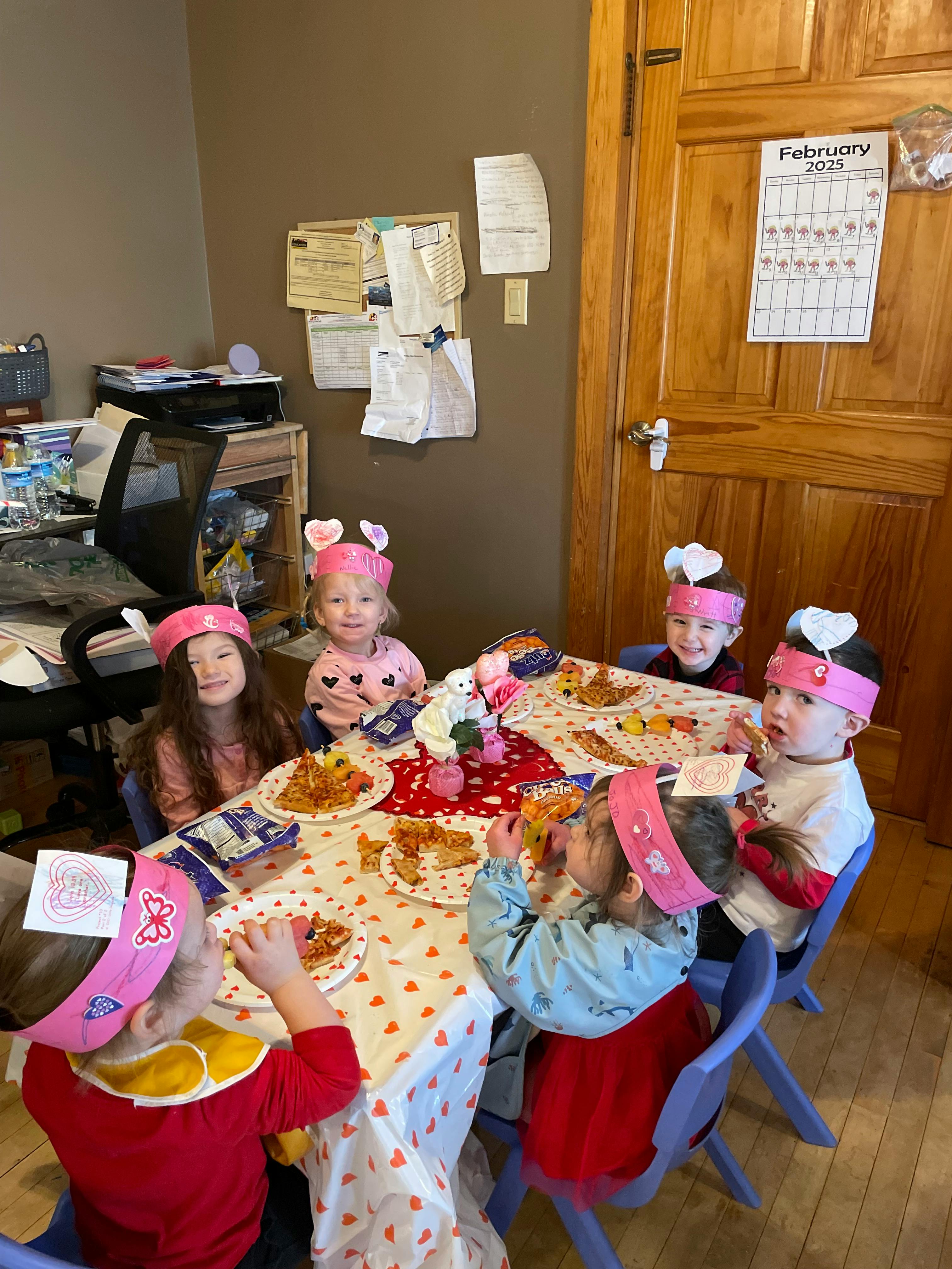 Children wearing headbands eating pizza at a table