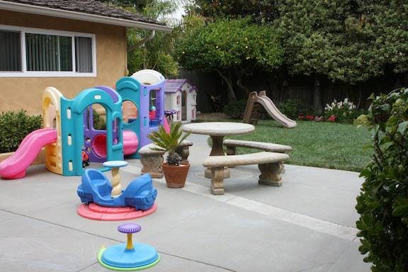 Outdoor play area with colorful plastic play structures and a slide
